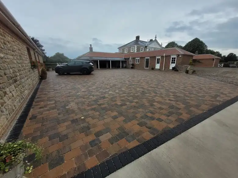 Block paved courtyard beside a stone house