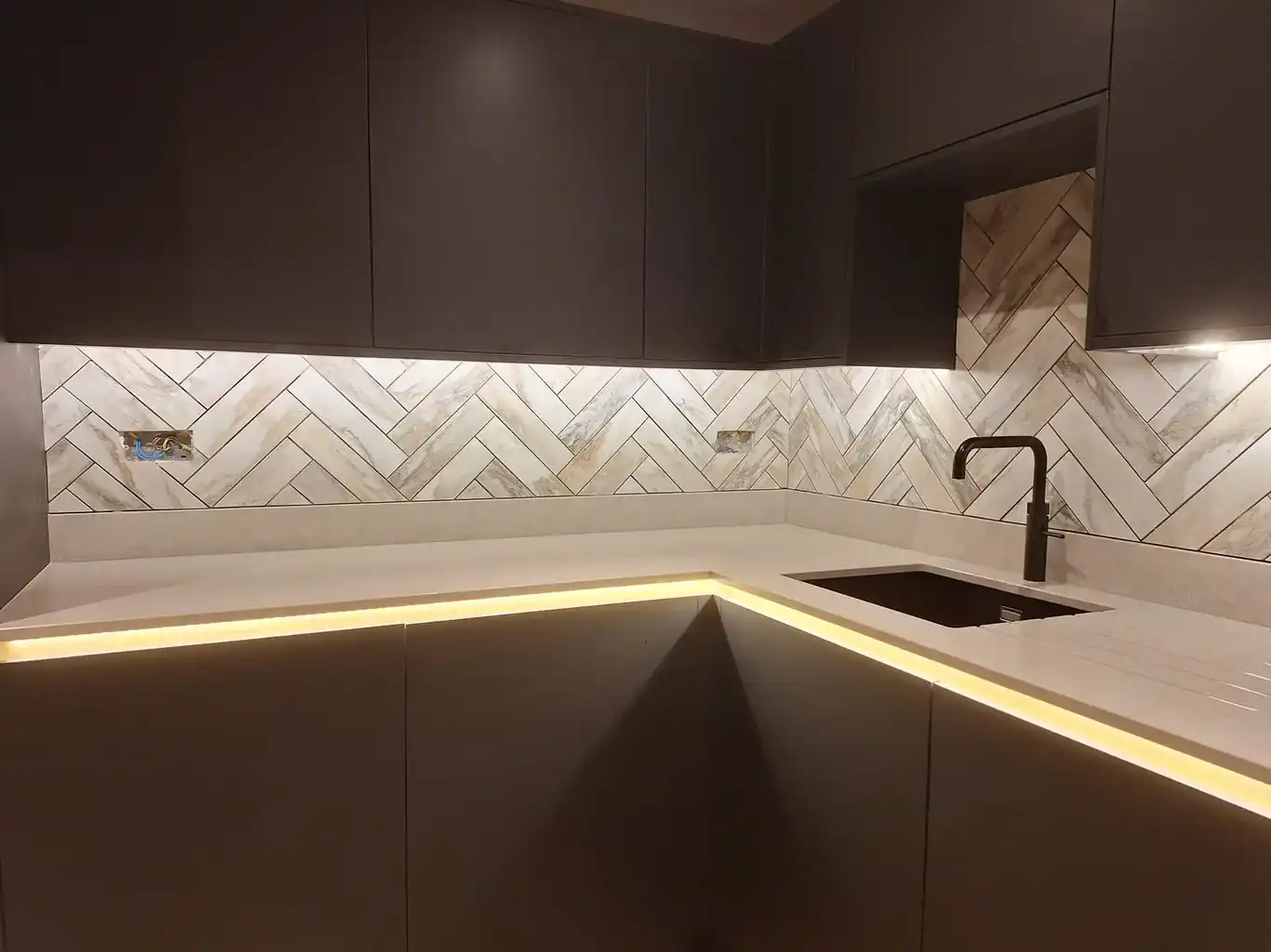 Dark handleless kitchen with lit plinths