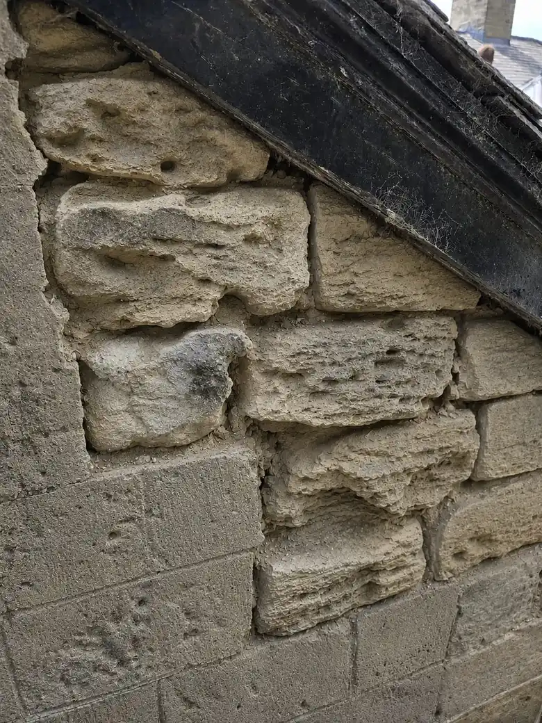 Eroded stones in a sandstone gable before repair