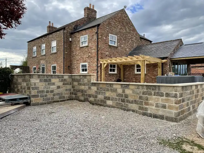 Farmhouse with new stone walls and a gravel drive