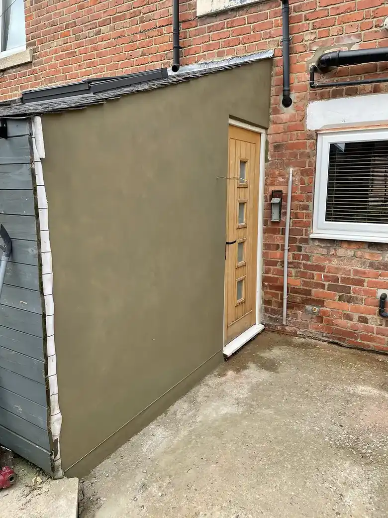 Fresh render on the side of a brick house