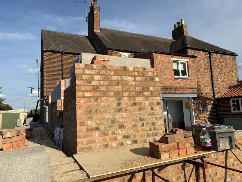 New brick walls rising at the back of the farmhouse