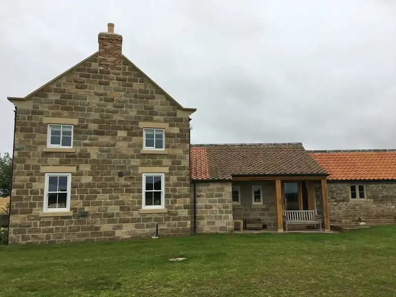 Stone farmhouse new build by Barlow Construction with pantile outbuildings