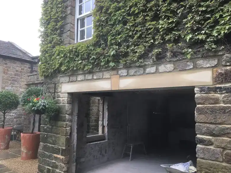 Stone house with a new opening under ivy