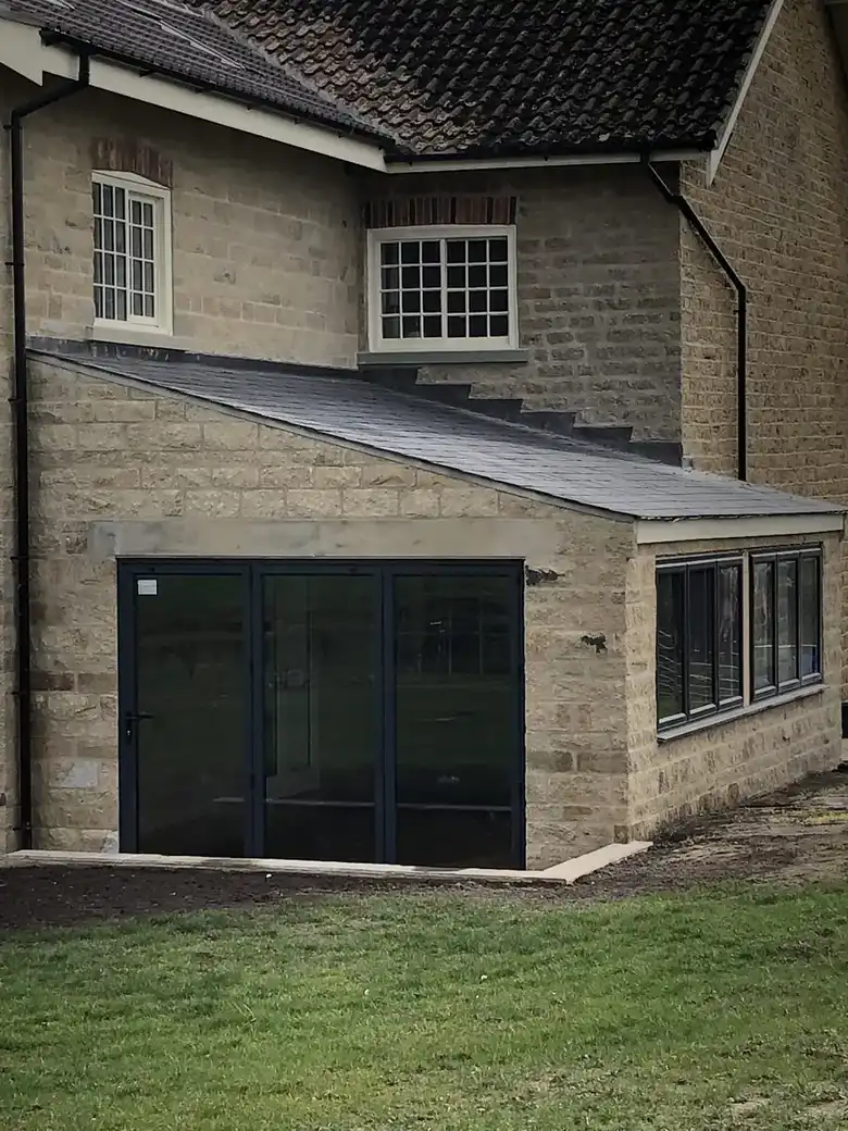 Stone single storey extension with dark glazing