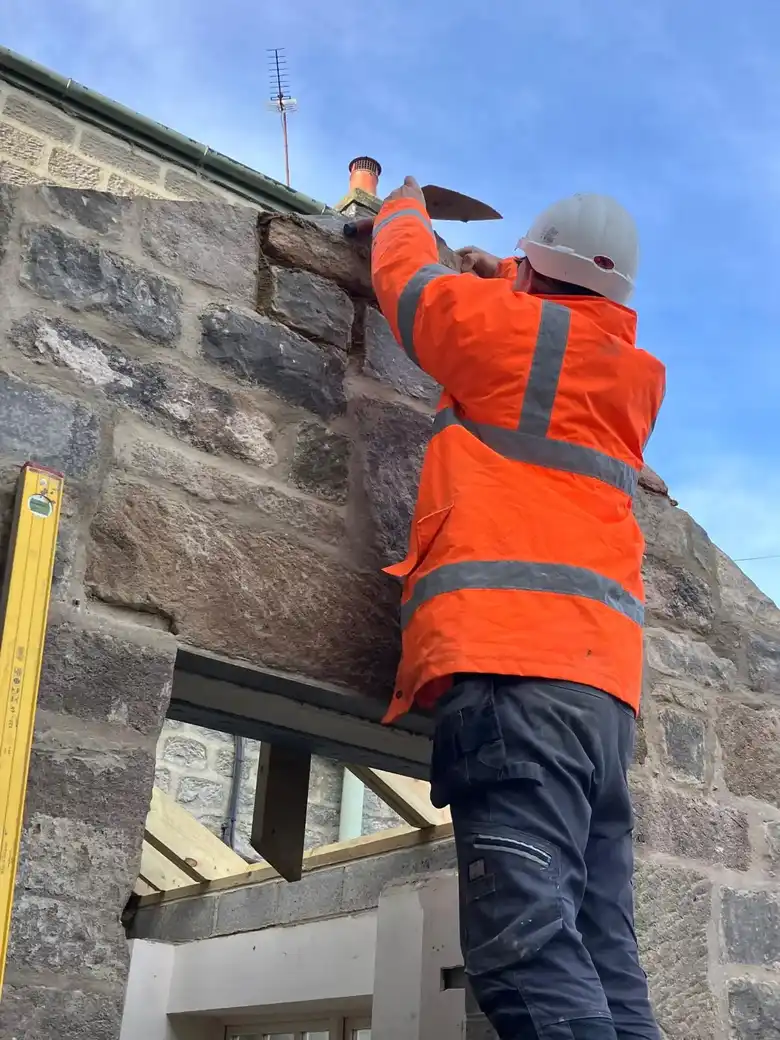 Stonemason rebuilding a stone gable on scaffold