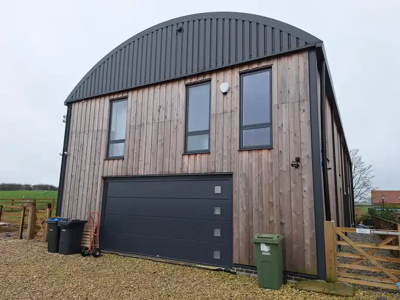 Timber clad Dutch barn house at Whenby with a curved roof