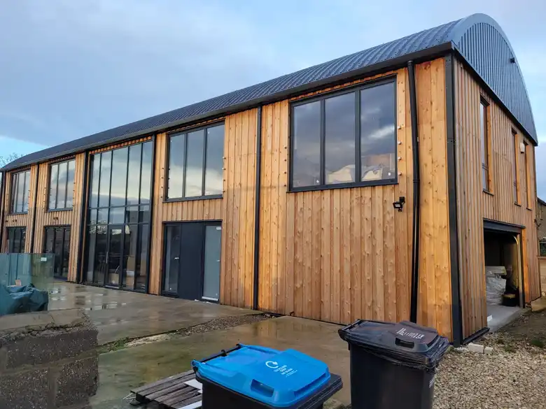 Timber clad new build with curved metal roof